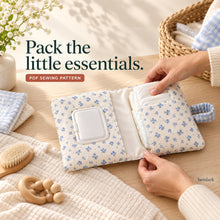 Hands slide folded diapers into the blue floral wallet pocket while a wipes pack is held in the opposite access-window pocket.