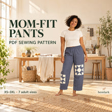 Adult model in slate-blue relaxed elastic-waist pants with offset ivory quilt-star patches in a sunlit atelier. PDF pattern in seven adult sizes XS-3XL.