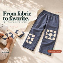 Slate-blue relaxed pants with ivory quilt-star patches lie beside hands sewing a matching block. Dimensional paper styling introduces the Mom-Fit Pants PDF pattern.